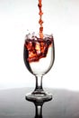 Pouring red wine into a glass of water Royalty Free Stock Photo