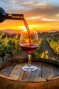 Pouring red wine into glass on wooden barrel in the vineyard at golden hour sunset. AI Generated Royalty Free Stock Photo