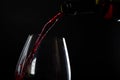 Pouring red wine with splashes and drops into a glass on a black background Royalty Free Stock Photo