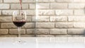 Pouring red wine into a wine glass against a white brick wall background,a beautiful glass with wine,an alcoholic drink. Royalty Free Stock Photo