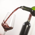 Pouring red wine into wineglass from green bottle Royalty Free Stock Photo