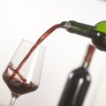 Pouring red wine into wineglass from green bottle Royalty Free Stock Photo