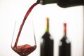 Pouring red wine into wineglass from green bottle Royalty Free Stock Photo