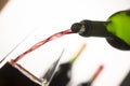 Pouring red wine into wineglass from green bottle Royalty Free Stock Photo