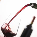 Pouring red wine into wineglass from green bottle Royalty Free Stock Photo