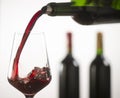 Pouring red wine into wineglass from green bottle Royalty Free Stock Photo