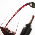 Pouring red wine into wineglass from green bottle Royalty Free Stock Photo