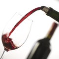 Pouring red wine into wineglass from green bottle Royalty Free Stock Photo