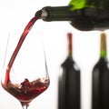 Pouring red wine into wineglass from green bottle Royalty Free Stock Photo