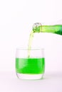 Pouring a refreshing green bubbly soda drink from bottle into glass on white background closeup Royalty Free Stock Photo