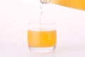 Pouring a refreshing orange, yellow soda drink from bottle into glass on white background. Royalty Free Stock Photo