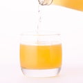 Pouring a refreshing orange, yellow soda drink from bottle into glass on white background, close up Royalty Free Stock Photo