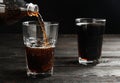 Pouring refreshing soda drink into glass on black wooden table against background Royalty Free Stock Photo