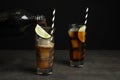 Pouring refreshing soda drink into glass on table against black background Royalty Free Stock Photo