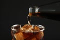 Pouring refreshing soda water from bottle into glass on black background, closeup Royalty Free Stock Photo