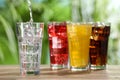 Pouring refreshing soda water into glass with ice cubes on wooden table outdoors Royalty Free Stock Photo