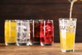 Pouring refreshing soda water in glass with ice cubes on wooden table, space for text Royalty Free Stock Photo