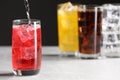 Pouring refreshing soda water into glass with ice cubes on white table, space for text Royalty Free Stock Photo