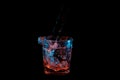 Pouring into a rocks glass and splashing out under blue and orange lights isolated on a black background Royalty Free Stock Photo