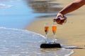 Pouring of rose champagne or cava sparkling wine served on white sandy tropical beach and blue ocean water, romantic vacation, Royalty Free Stock Photo