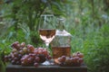 Pouring rose wine from a bottle into glass on table with pink grapes Royalty Free Stock Photo