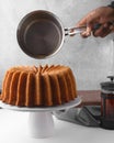 Pouring a rum sauce on rum bundt cake Royalty Free Stock Photo