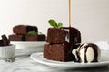 Pouring sauce onto fresh brownies served with ice-cream on plate. Delicious chocolate pie