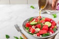 Pouring sauce in a plate with summer fruit and vegetable salad made of watermelon, cucumber, cheese and onion Royalty Free Stock Photo