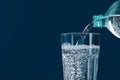 Pouring soda water from bottle into glass on blue background, closeup. Space for text Royalty Free Stock Photo