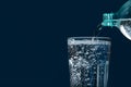 Pouring soda water from bottle into glass on blue background, closeup. Space for text Royalty Free Stock Photo