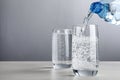 Pouring soda water from bottle into glass on grey background. Space for text Royalty Free Stock Photo