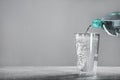 Pouring soda water from bottle into glass on grey table. Space for text Royalty Free Stock Photo