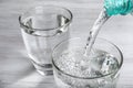 Pouring soda water from bottle into glass on white wooden table, closeup Royalty Free Stock Photo