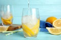 Pouring soda water into glass with lemon slices and ice cubes at light blue wooden table Royalty Free Stock Photo