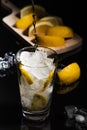 Pouring Sparkling cold water detox with lemon slices and ice on a dark glass background with black back Royalty Free Stock Photo