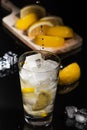 Pouring Sparkling cold water detox with lemon slices and ice on a dark glass background with black back Royalty Free Stock Photo