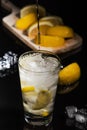 Pouring Sparkling cold water detox with lemon slices and ice on a dark glass background with black back Royalty Free Stock Photo