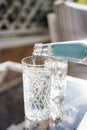 Pouring sparkling water from the bottle into glass. Water drink pouring into glass, garden background Royalty Free Stock Photo