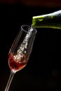 Pouring sparkling wine into a glass on a dark background