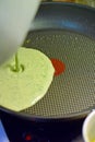 Pouring spinach pancake batter to frying pan. Royalty Free Stock Photo