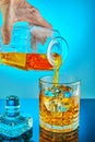 Pouring square crystal decanter with scotch tape whiskey or brandy in a crystal round glass on a blue gradient background with Royalty Free Stock Photo