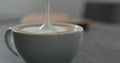 Pouring steamed milk anto espresso to make capuccino