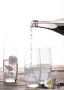 Pouring of stil mineral drink water in glasses with ice cubes cl