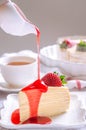 Pouring strawberry sauce onto delicious crepe cake on white plate. The concept of emotion atmosphere in the morning