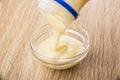 Pouring sweet condensed milk from bottle in transparent bowl Royalty Free Stock Photo