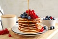 Pouring syrup onto pancakes with fresh berries