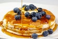 Pouring syrup over the butter on the blueberry stack of pancakes on the kitchen table waiting to be eaten Royalty Free Stock Photo