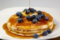 Pouring syrup over the butter on the blueberry stack of pancakes on the kitchen table waiting to be eaten Royalty Free Stock Photo