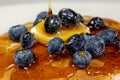 Pouring syrup over the butter on the blueberry stack of pancakes on the kitchen table waiting to be eaten Royalty Free Stock Photo