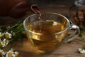 Pouring tasty chamomile tea into glass cup on table Royalty Free Stock Photo